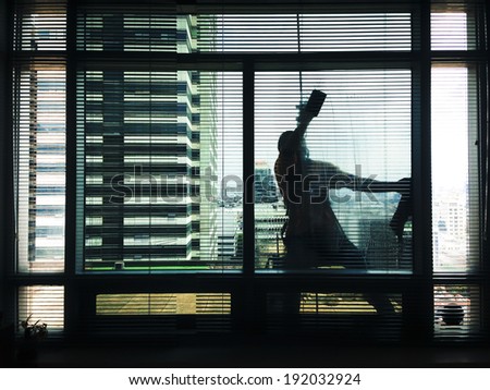 BANGKOK / THAILAND - APRIL 2103 : a worker cleans the outside window of JTC office building on April, 2014 in Bangkok, Thailand