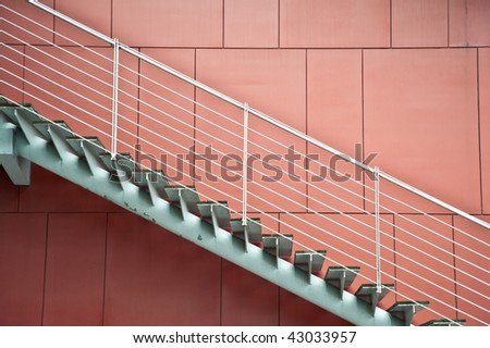 A metal stair in front of a red background