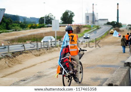 PONTEVEDRA, SPAIN - JUNE 11: A man on a bicycle with a flag during Demonstration of ecologists for the closure of the pulp mill in the Ria of Pontevedra in Galicia, June 11, 2011 in Pontevedra, Spain.