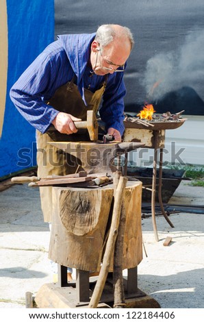 CAMINHA - JULY 14: A blacksmith in medieval clothes, working in the street During The Medieval Fair celebrated in Caminha, Portugal on July 14, 2012 in Caminha, Portugal.