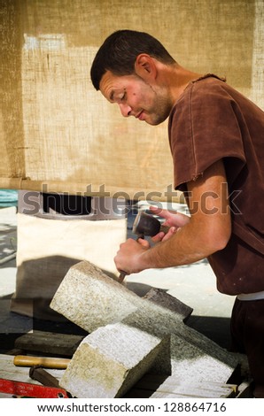 PONTEVEDRA - SEPTEMBER 1: A mason works a piece of granite stone under the eyes of curious during the Medieval Celebration of September 1, 2012, in Pontevedra, Spain.