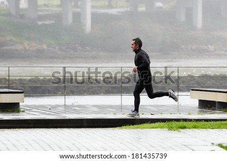 Pontevedra, SPAIN - MARCH 2, 2014: A man practice track and field one day of heavy rain, on a track for running and walking in the city of Pontevedra.