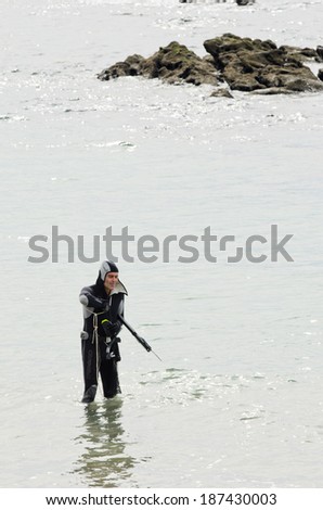 SANXENXO, SPAIN - MARCH 9, 2014: A man in neoprene suit ready to dive into the waters of the sea in the urban beach Silgar a sunny March day, in the region of Rias Baixas tourist in Galicia.