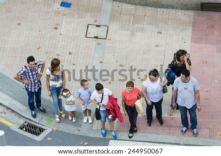 PONTEVEDRA, SPAIN - AUGUST 9, 2014: A group of people waiting time to cross the street at a crosswalk in the city.