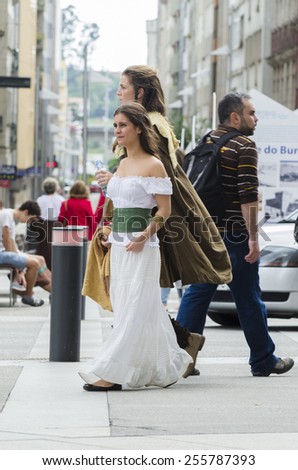 PONTEVEDRA, SPAIN - SEPTEMBER 6, 2014: A young girls walking, dressed in colorful costumes of the Middle Ages, in medieval festival held each year in the historical district of the city.