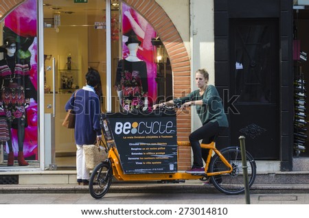 TOLOUSE, FRANCE - OCTOBER 4, 2014: A woman driving a bicycleÃ?Â of distribution in the historic city center.