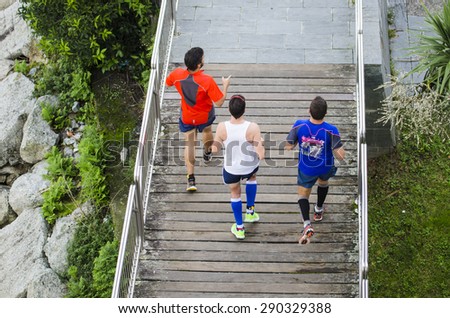 PONTEVEDRA, SPAIN - OCTOBER 19, 2014: Three men practice running on a boardwalk, at one of the banks of the river which crosses the city.