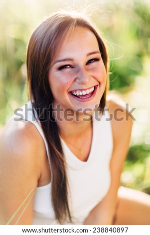 Portrait of an Attractive Young Woman Sitting in Grass Laughing and Smiling