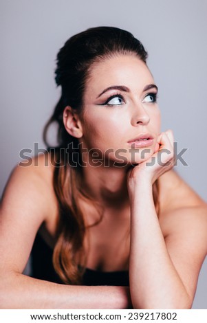 Studio Portrait of Young Attractive Woman looking bored with hand on face looking away from camera