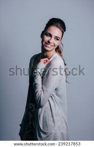 Studio Portrait of Young Attractive Woman sweater on looking away from camera hand on shoulder laughing