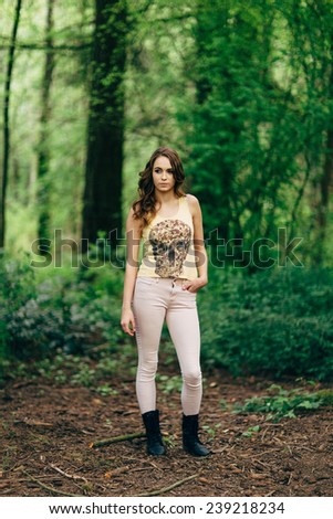 Portrait of Young Attractive Woman in the forest with a skull t-shirt and hand in pocket looking away from camera