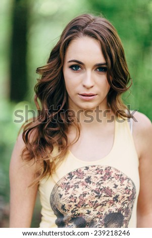 Portrait of Young Attractive Woman in the forest with a skull t-shirt and hand in pocket looking at camera