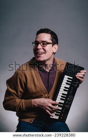 cheesy portrait of a man smiling silly at his piano keyboard looking away from camera