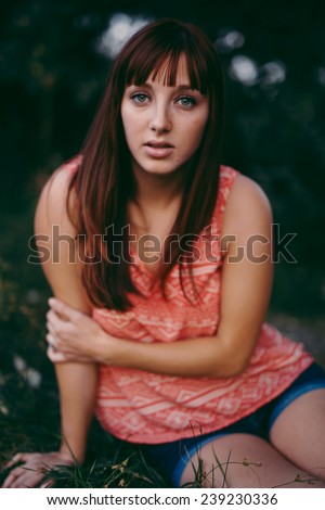 portrait of beautiful young female staring at camera in a small grassy area beautiful pose hand on arm