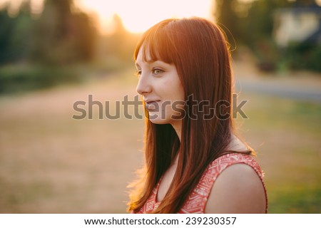 portrait of beautiful young female sun behind head looking off camera slight smile side shot