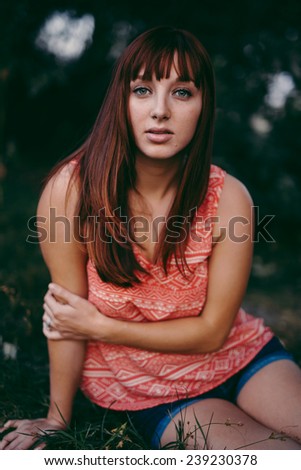 portrait of beautiful young female staring at camera in a small grassy area beautiful pose hand on arm slight variation