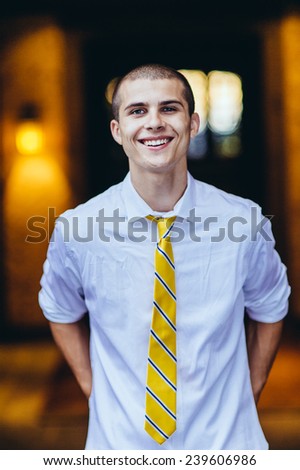 young male student, with tie, smiling, arms behind back