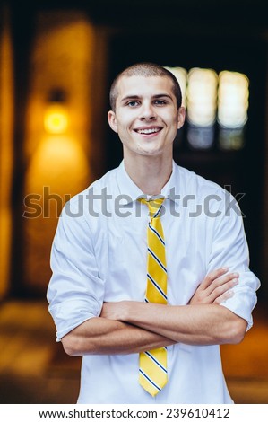 young male student, with tie, smiling, arms folded