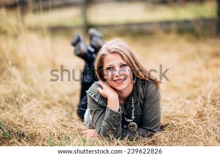 Attractive Young Blond Woman laying in straw feet up laughing, hand on shoulder