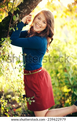 Attractive Young Woman next to tree kicking feet up and laughing