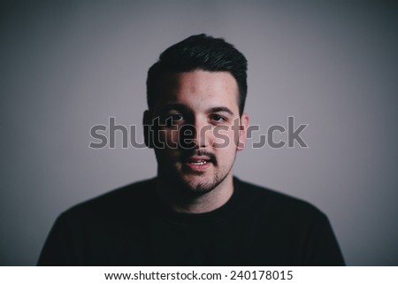 Low key portrait of a serious man in his late twenties slight smile