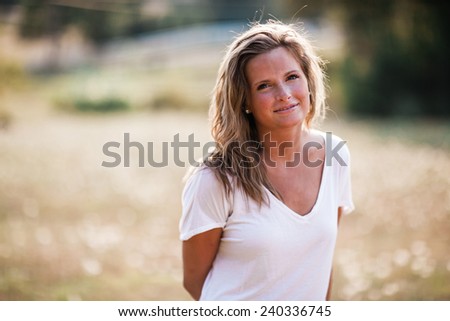 Beautiful Blonde Young Woman smiling at camera hands behind back