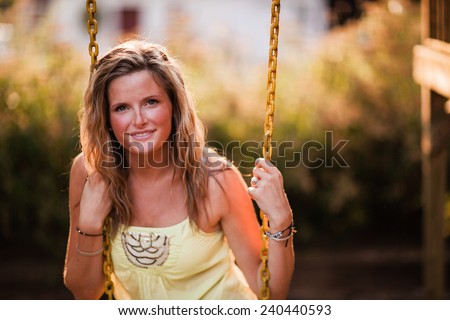 Beautiful Blonde Young Woman smiling on swing slight smile head against chain