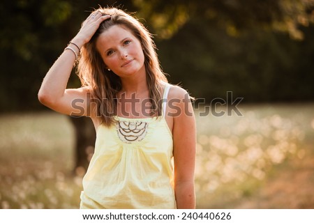 Beautiful Blonde Young Woman in sunset meadow summer day hand in hair