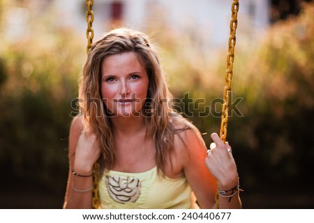 Beautiful Blonde Young Woman smiling on swing slight smile