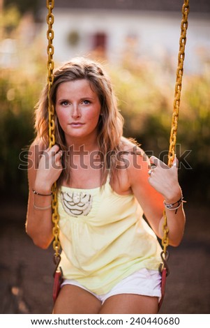 Beautiful Blonde Young Woman smiling on swing no smile head against chain vertical