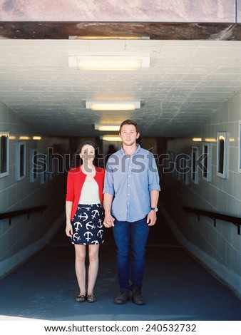 Attractive Young Couple Standing straight on underneath a walkway no smile