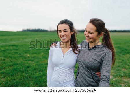 Young Adult Female Runners Arms Around each other smiling in country