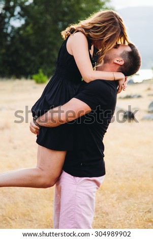Beautiful Couple girl being lifted up river background kissing