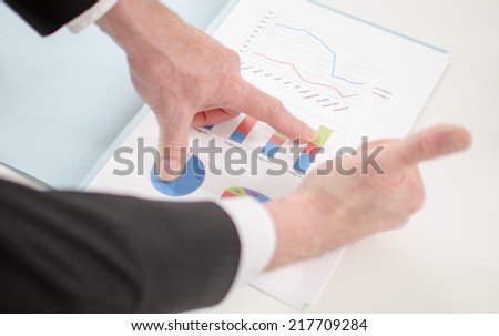 Businessman with thumbs up before graphs showing positive results