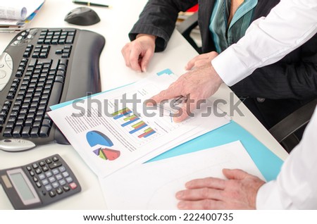 Workteam in office, businessman showing a graph with his index finger