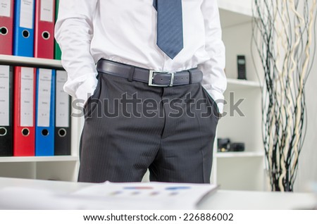 Business man standing with his hands in pockets at office