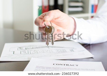 Estate agent holding house keys over a contract