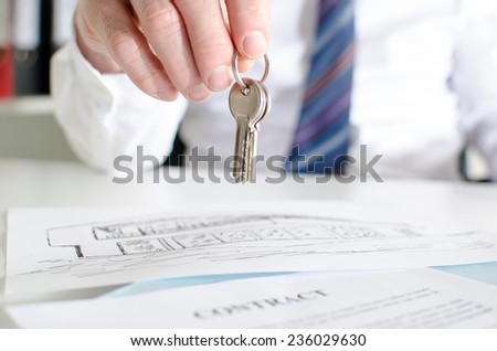 Estate agent holding house keys over a contract