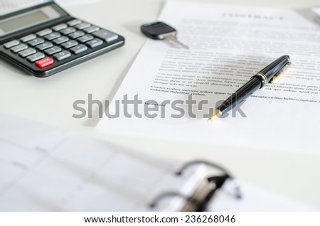 Sales contract, key, pen and calculator on a desk