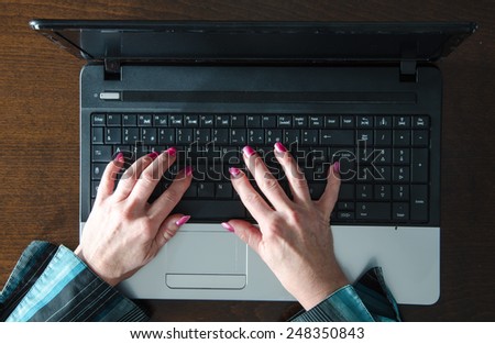 Female hands typing on a laptop, top view