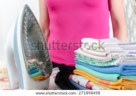 Woman standing behind the iron and the ironed linen