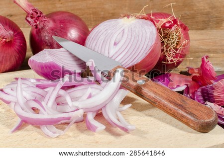 Fresh sliced and whole red onions on wooden background