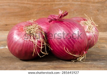 Fresh bulbs of red onions on wooden background