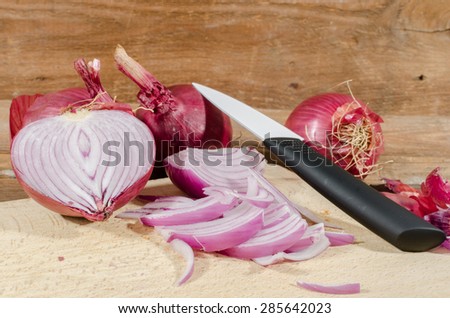 Fresh sliced and whole red onions on wooden background