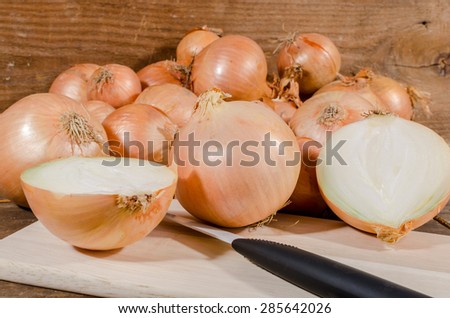 Fresh half and whole onions on wooden background