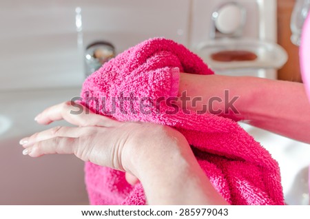 Woman drying her hands with a pink towel