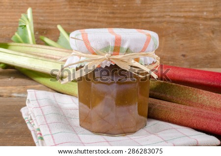 Rhubarb stalks with rhubarb jam jar on wooden background
