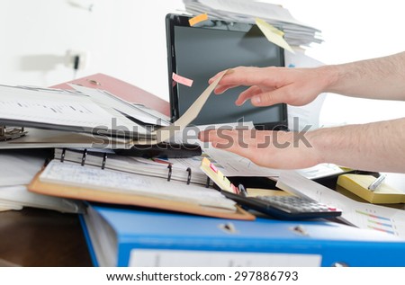Businessman looking for his phone on his messy desk