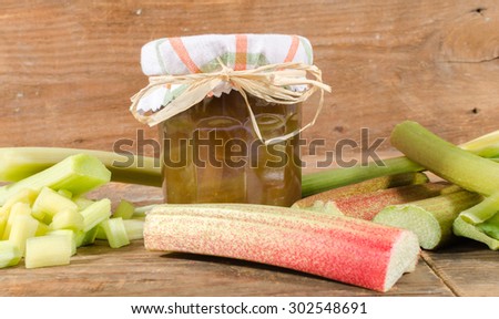 Rhubarb jam jar with fresh rhubarb on wooden background