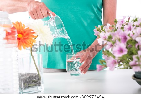 Woman pouring water from a pitcher into a glass